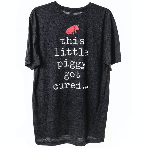 The back of a black shirt with il porcellino salumi's pig logo at the top and the words "this little piggy got cured..." below the logo.